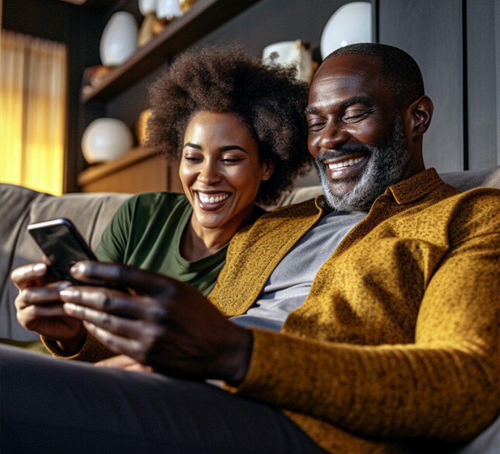 Lachende vrouw en man kijkend naar een smartphone.